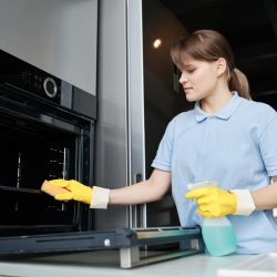 Woman cleaning the oven in the kitchen